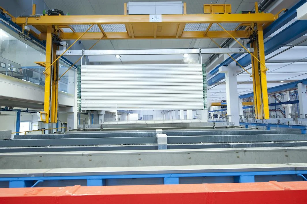 Yellow overhead gantry crane above an anodizing tank line.