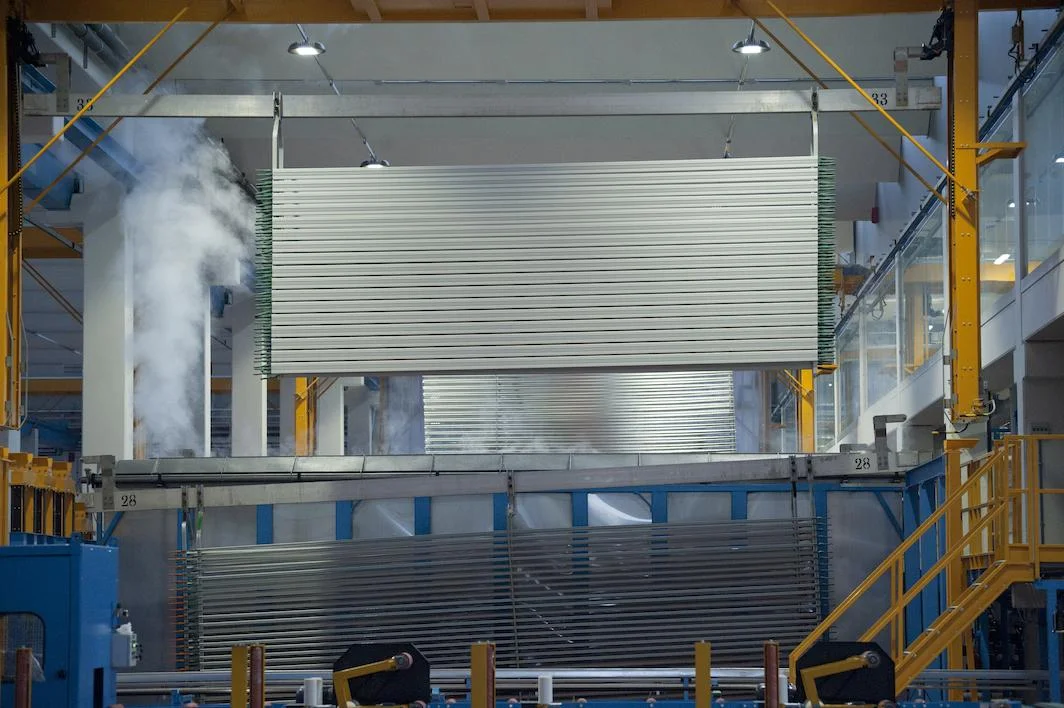 Rinse mist rising from an anodizing tank as a profile rack is lowered.