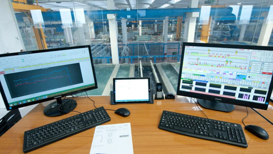 Operator workstation with monitors displaying extrusion plant management software.